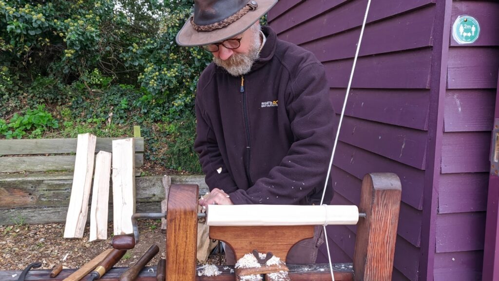 A man turns wood on a pole lathe